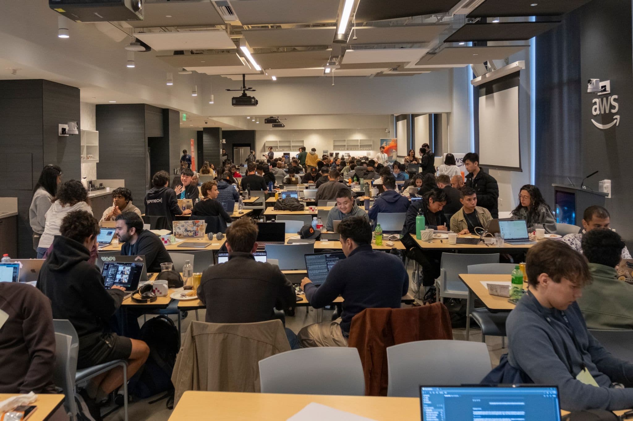 Developers building at a packed hackathon hosted in a partner workspace.