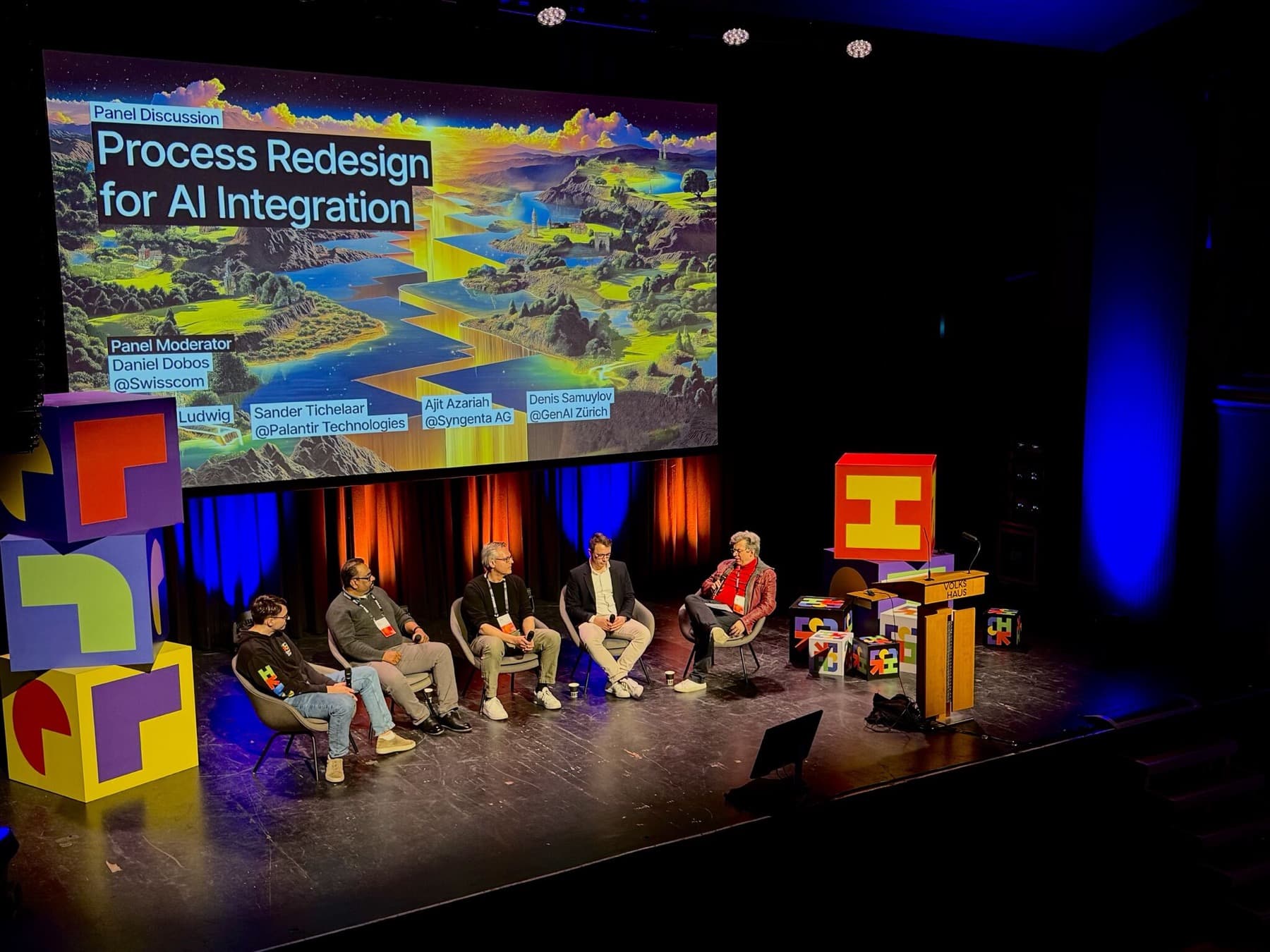Panelists on stage discussing process redesign for AI integration at a conference-style summit.